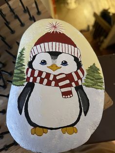 a painted rock with a penguin wearing a hat and scarf