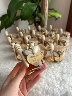 a hand holding a bottle of honey and some cookies in the shape of heart on top of it