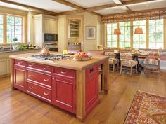 a large kitchen with red cabinets and wooden floors