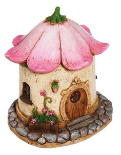 a small house with a pink roof and flowers on the top is sitting on some rocks