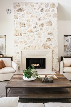 a living room with two couches and a coffee table in front of a stone fireplace