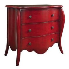 a red dresser with three drawers and two pulls on the bottom drawer, in an ornate style