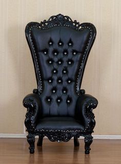 a black leather chair sitting on top of a hard wood floor next to a wall