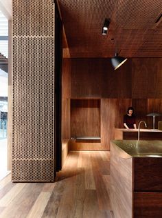 a person sitting in a room with wooden walls and flooring on the other side