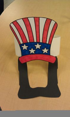 a paper hat sitting on top of a wooden table in the shape of an american flag