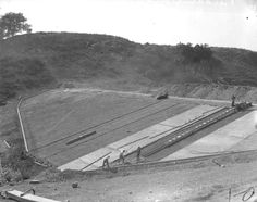 an old black and white photo of men working on a construction site in the mountains