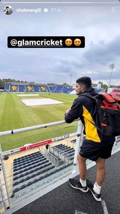 a man with a back pack is standing on the bleachers at a soccer stadium