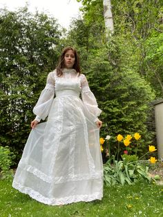 a woman wearing a white dress standing in the grass