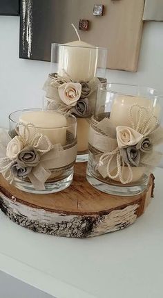 some candles are sitting on top of a piece of wood with flowers and ribbons around them