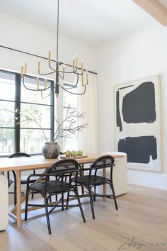 a dining room table with black chairs in front of a large painting on the wall