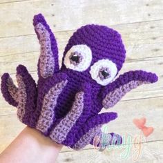 a hand that has a purple and white crocheted octopus on it