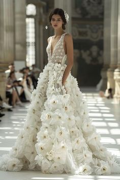 a model walks down the runway in a white wedding dress with flowers on her skirt