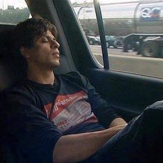 a man sitting in the back seat of a car with his eyes closed and head down