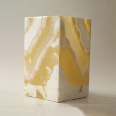 a white and yellow vase sitting on top of a table