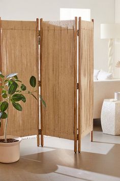 a room divider made out of bamboo sticks with a potted plant next to it