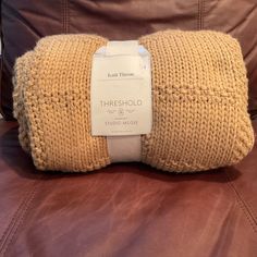 there is a brown couch with a white tag on the pillow that says,'knitted throw '