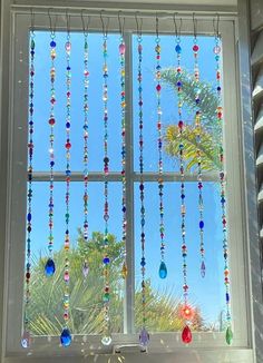 a window with beads hanging from it's side and palm trees in the background