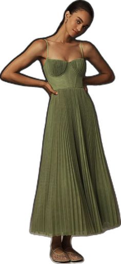 a woman in a green dress is standing with her hands on her hips and looking at the camera