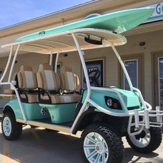 a blue golf cart parked in front of a building with a surfboard on top