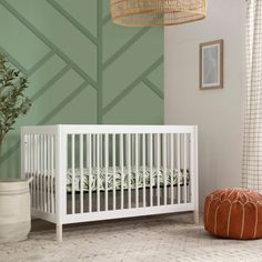 a white crib sitting next to a green wall