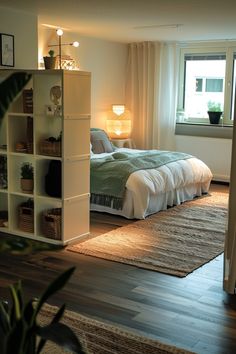 a bedroom with a bed, bookcases and plants in the window sill