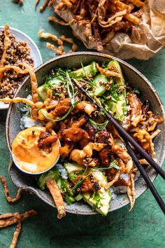 a bowl filled with food and chopsticks on top of a green tablecloth