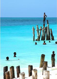 a man standing on top of a wooden structure in the middle of blue ocean water