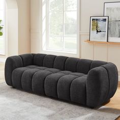 a gray couch sitting on top of a rug in a living room next to a window