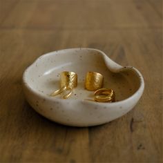 two gold rings in a white bowl on a wooden table