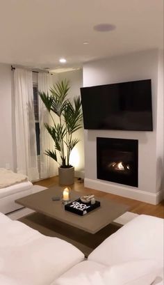 a living room filled with white furniture and a flat screen tv mounted on the wall