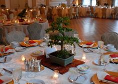 a table set for an event with place settings, candles and plates on the table