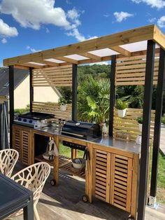 an outdoor kitchen with grill, table and chairs