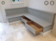 a corner bench with drawers underneath it in a room that has tile flooring and white walls