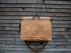 a brown leather bag hanging on the side of a building with wood siding behind it