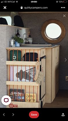 the inside of a camper with books and magazines in its storage compartment, as well as a round window