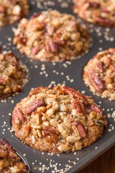 a muffin in a muffin tin with pecans and nuts on top, ready to be eaten