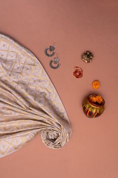 an assortment of jewelry is laid out on a pink surface with a cloth draped over it