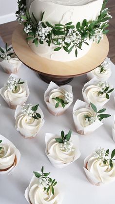 there are many cupcakes on the table with flowers and leaves around them,