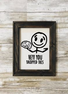 a wooden frame hanging on the side of a wall with a sign saying hey you dropped this