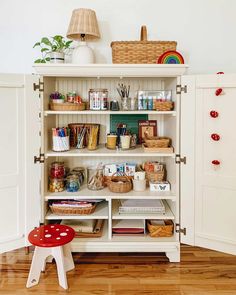 a white bookcase filled with lots of books and crafting supplies on top of a hard wood floor