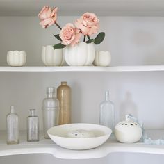 some vases and flowers are sitting on the shelves