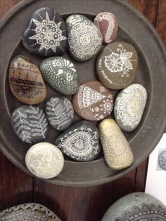 some rocks are sitting in a bowl on the table and one is decorated with paisley designs