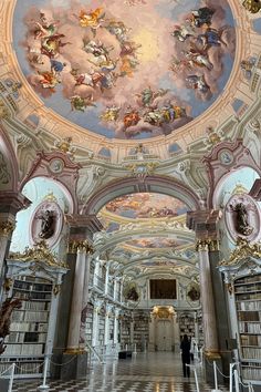 the ceiling is decorated with paintings and bookshelves in an ornate building, which also has a checkerboard floor