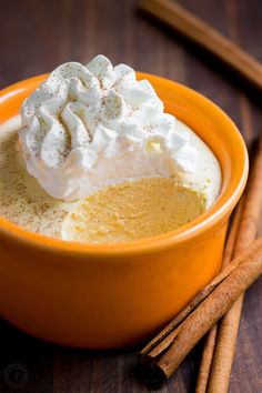 an orange bowl filled with whipped cream and cinnamon sticks