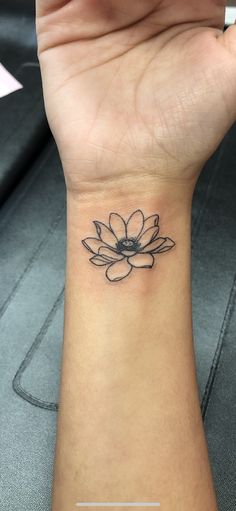 a woman's wrist tattoo with a black and white flower on the left side