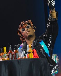 a man with sunglasses on sitting at a table full of bottles and condiments