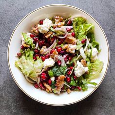 a white bowl filled with lettuce and pomegranate