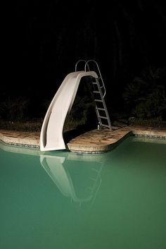 a ladder leaning over the edge of a pool at night