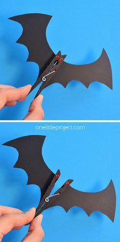 someone cutting out the shape of a bat with scissors to make it look like they are flying