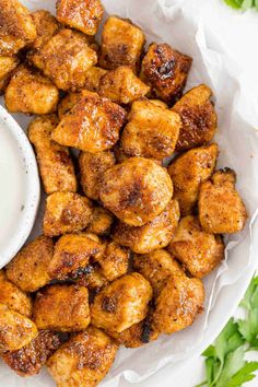 chicken wings with ranch dressing in a white bowl next to cilantro and parsley